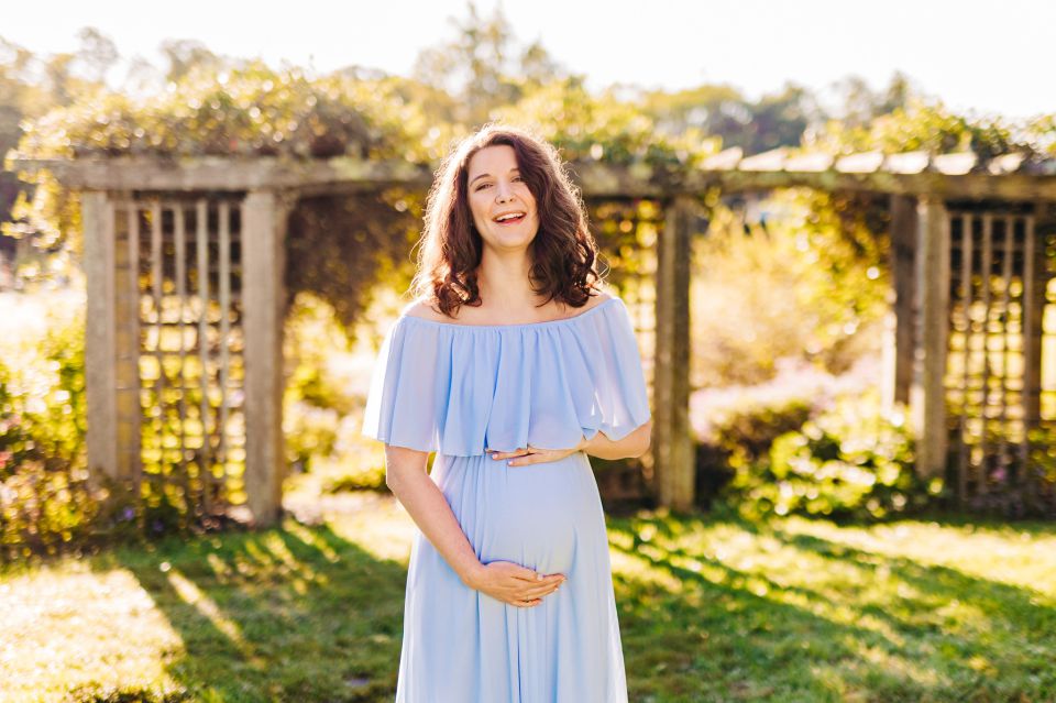 Young woman in light blue gown posing for maternity portraits at Green Spring Gardens in Alexandria, VA