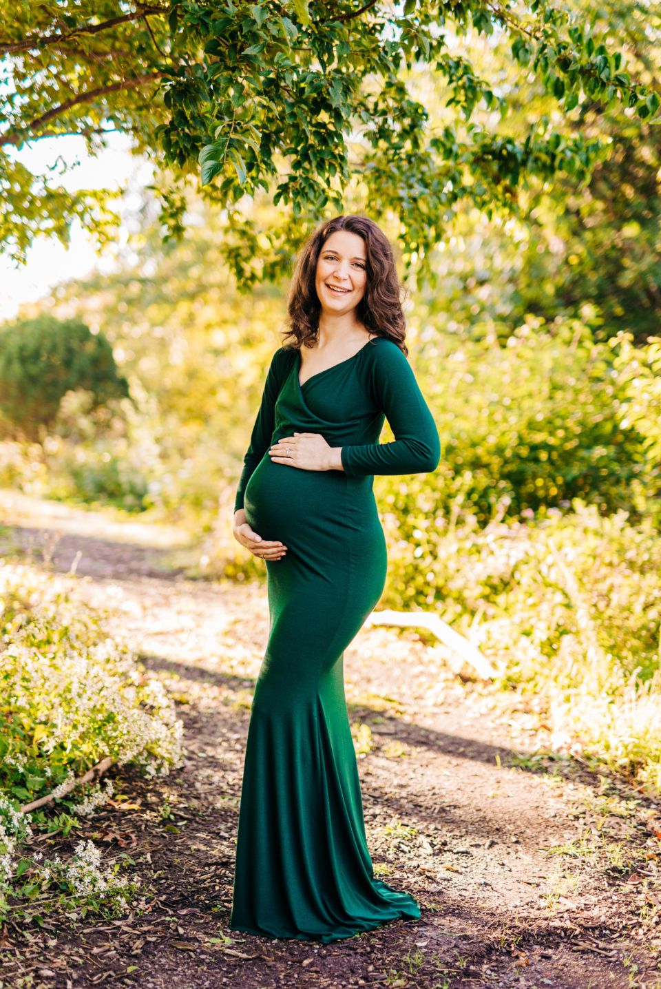 Woman in dark green dress posing for maternity portraits at Green Spring Gardens in Alexandria, VA