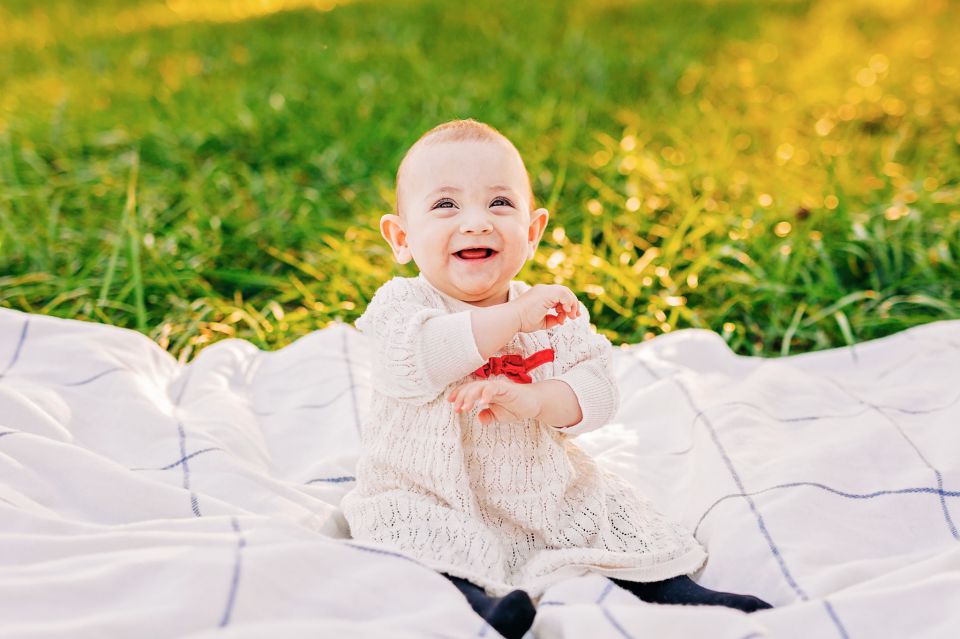 Laughing baby sitting on a white blanket at Manassas Battlefield Park