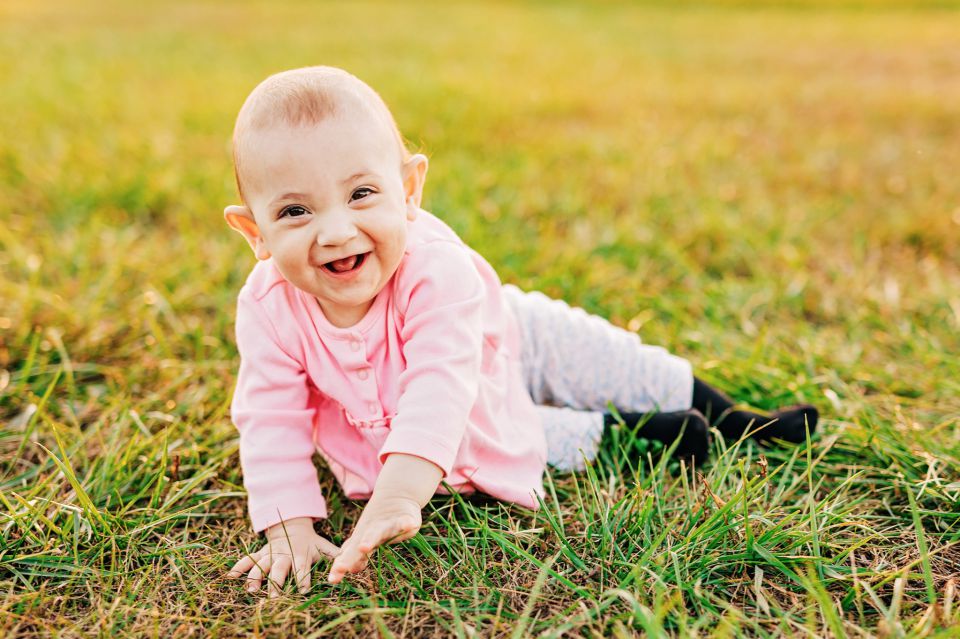 Laughing baby sitting in a grass field at Manassas Battlefield Park