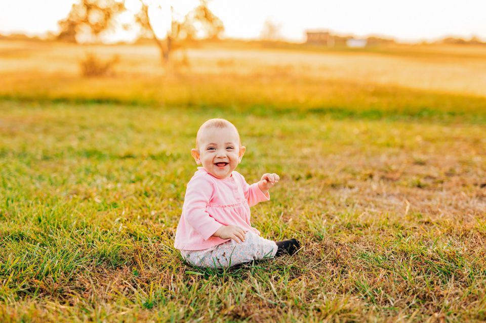 Laughing baby sitting in a grass field at Manassas Battlefield Park