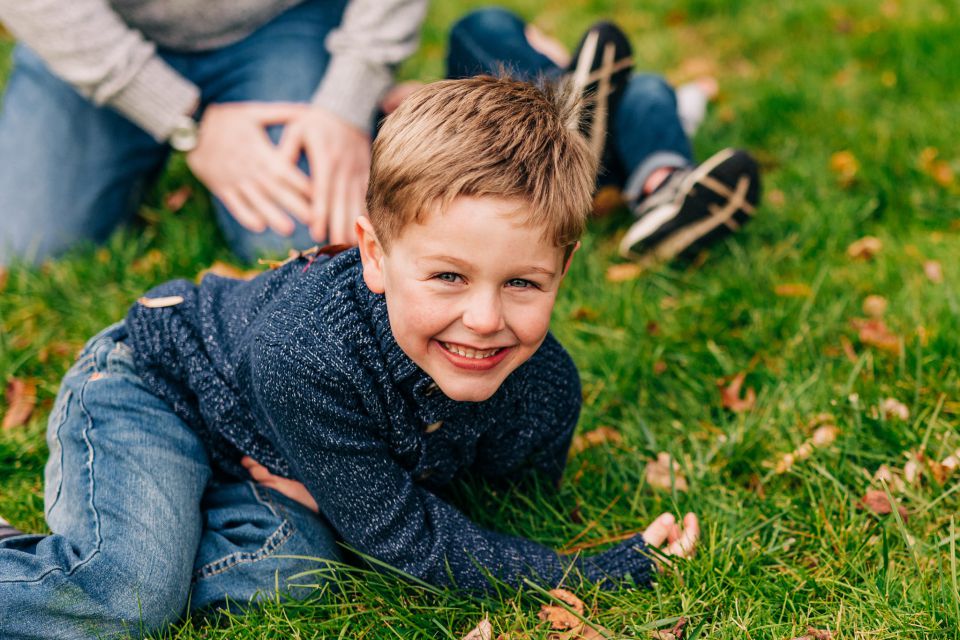 Young boy in blue sweater playing in the grass and laughing
