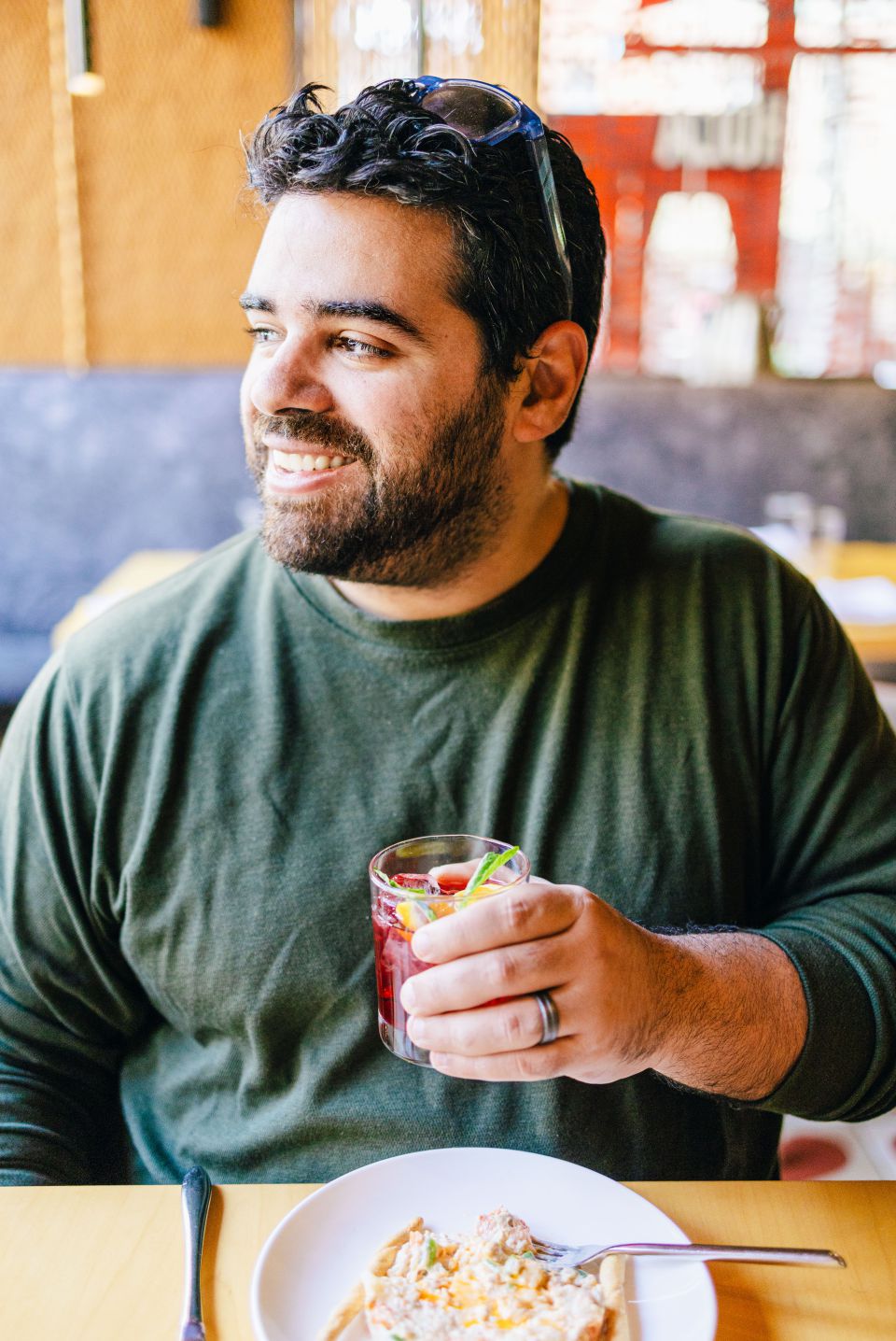 Bearded man in green shirt smiling and holding glass of sangria